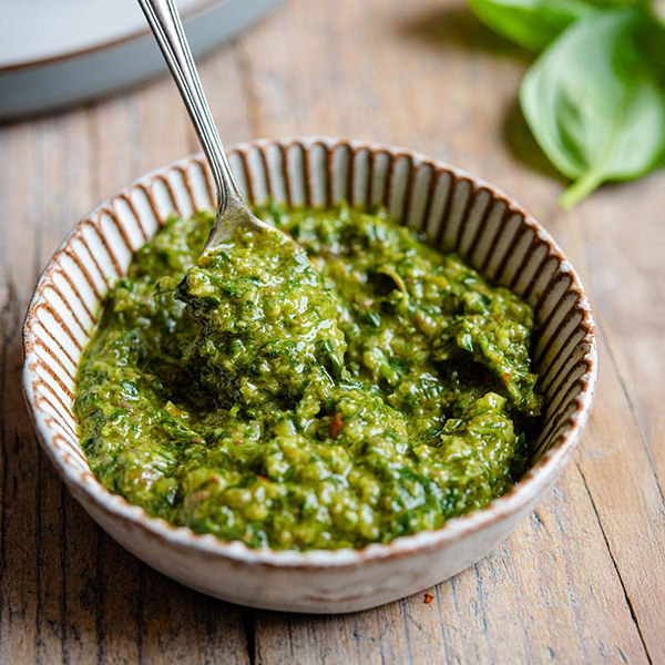 Traditionele Italiaanse salsa verde in een klein kommetje, gemaakt met peterselie, kappertjes, ansjovis, knoflook en extra vierge olijfolie, geserveerd met verse ingrediënten.